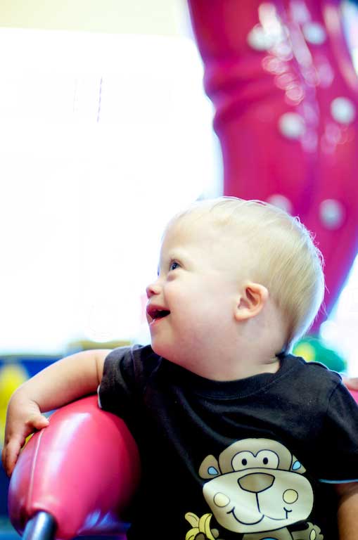 baby with down syndrome happy in haircut chair