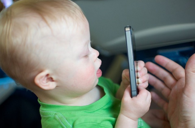 baby child with down syndrome playing using iphone airplane
