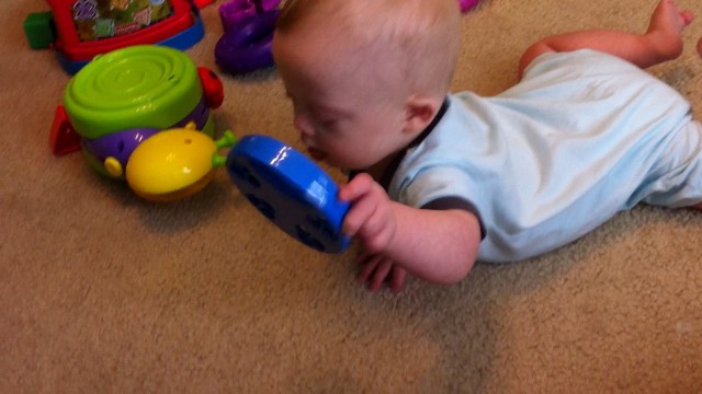 baby with down syndrome playing with toy tambourine