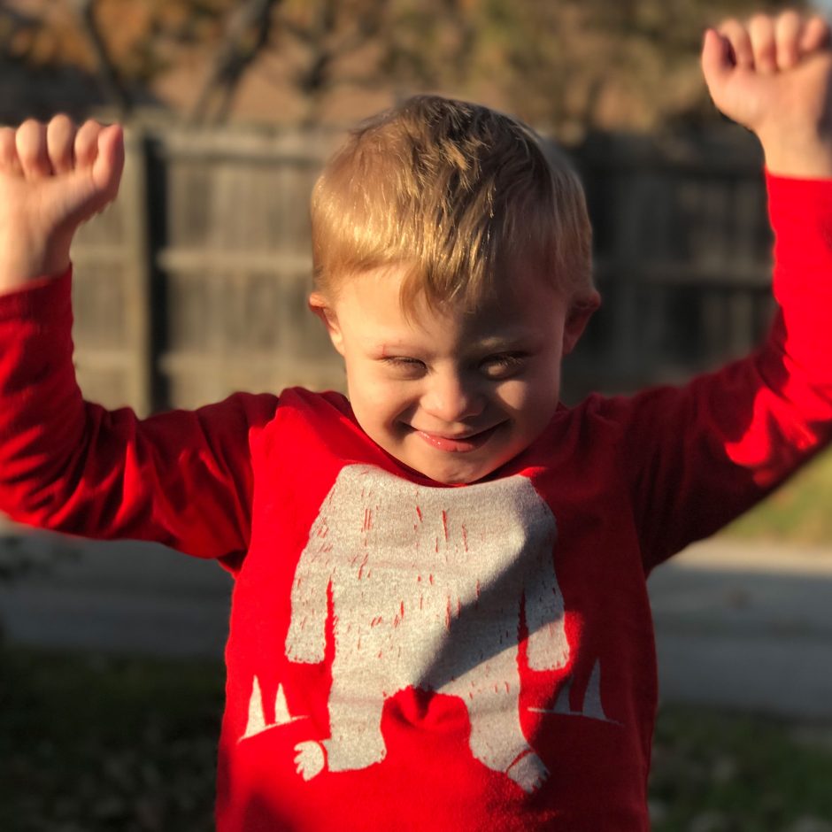 happy boy with down syndrome raising arms up