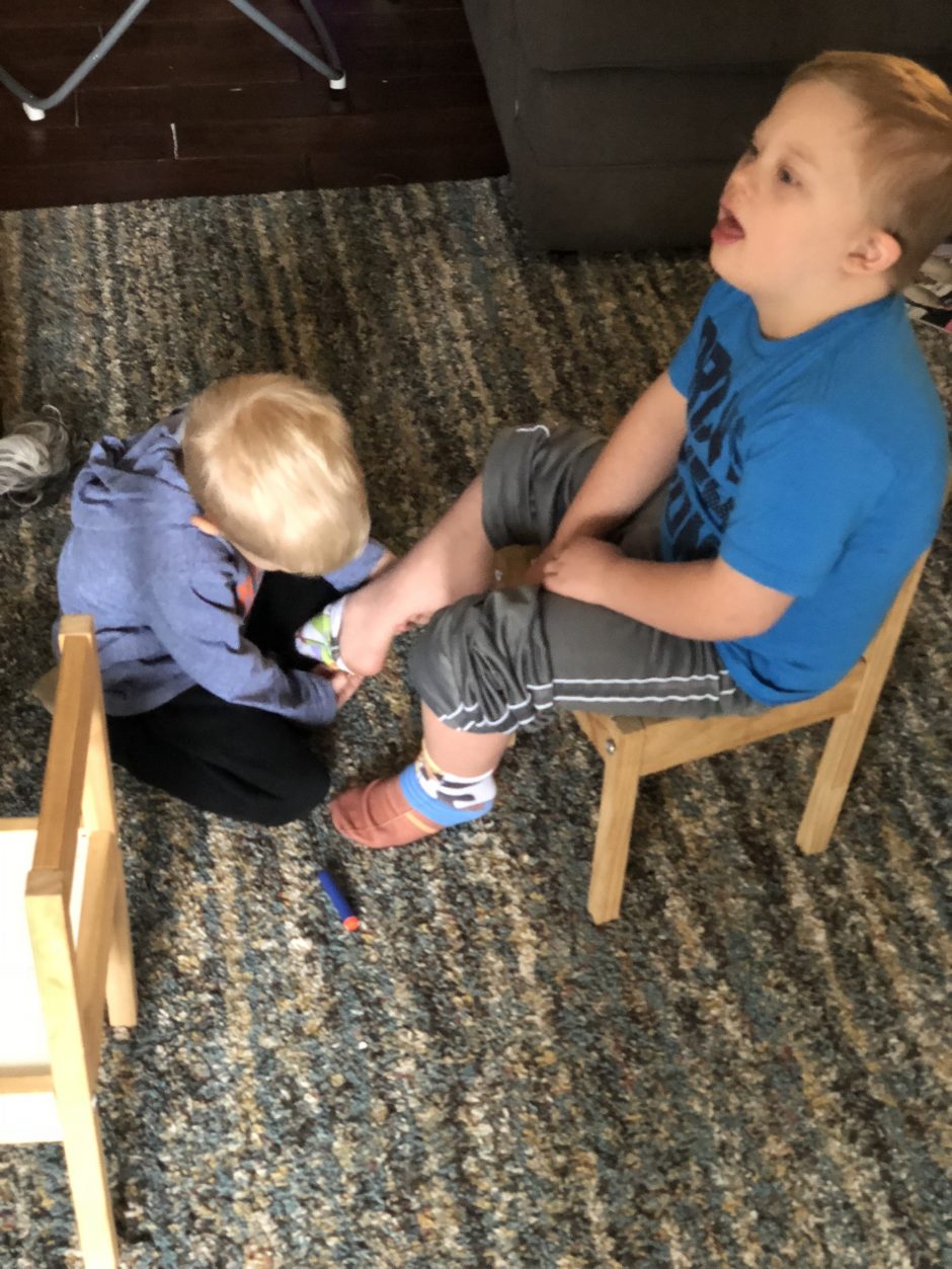 younger brother helping older brother with down syndrome socks