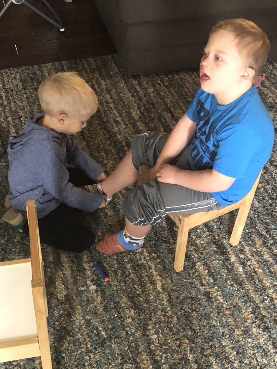 younger brother helping older brother with down syndrome socks